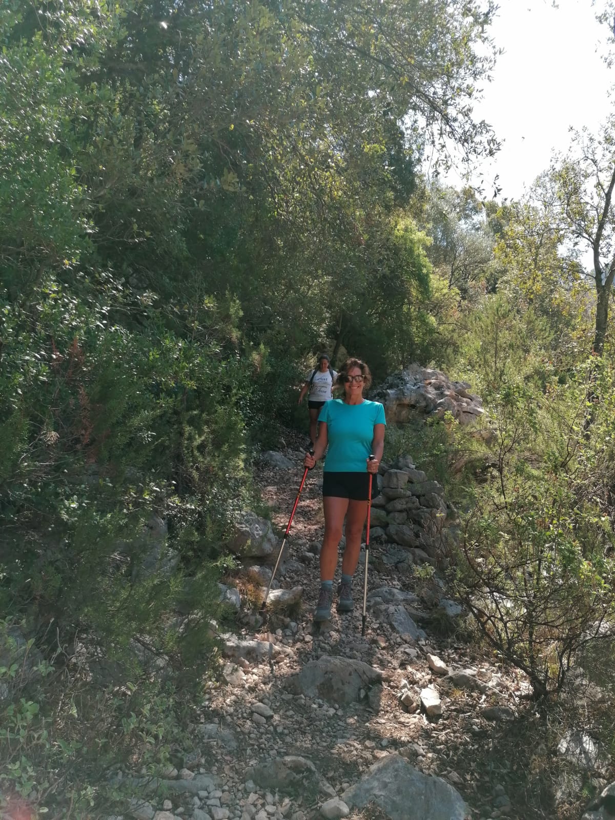 Maria Elena in montagna con i bastoncini da trekking su un sentiero di pietre