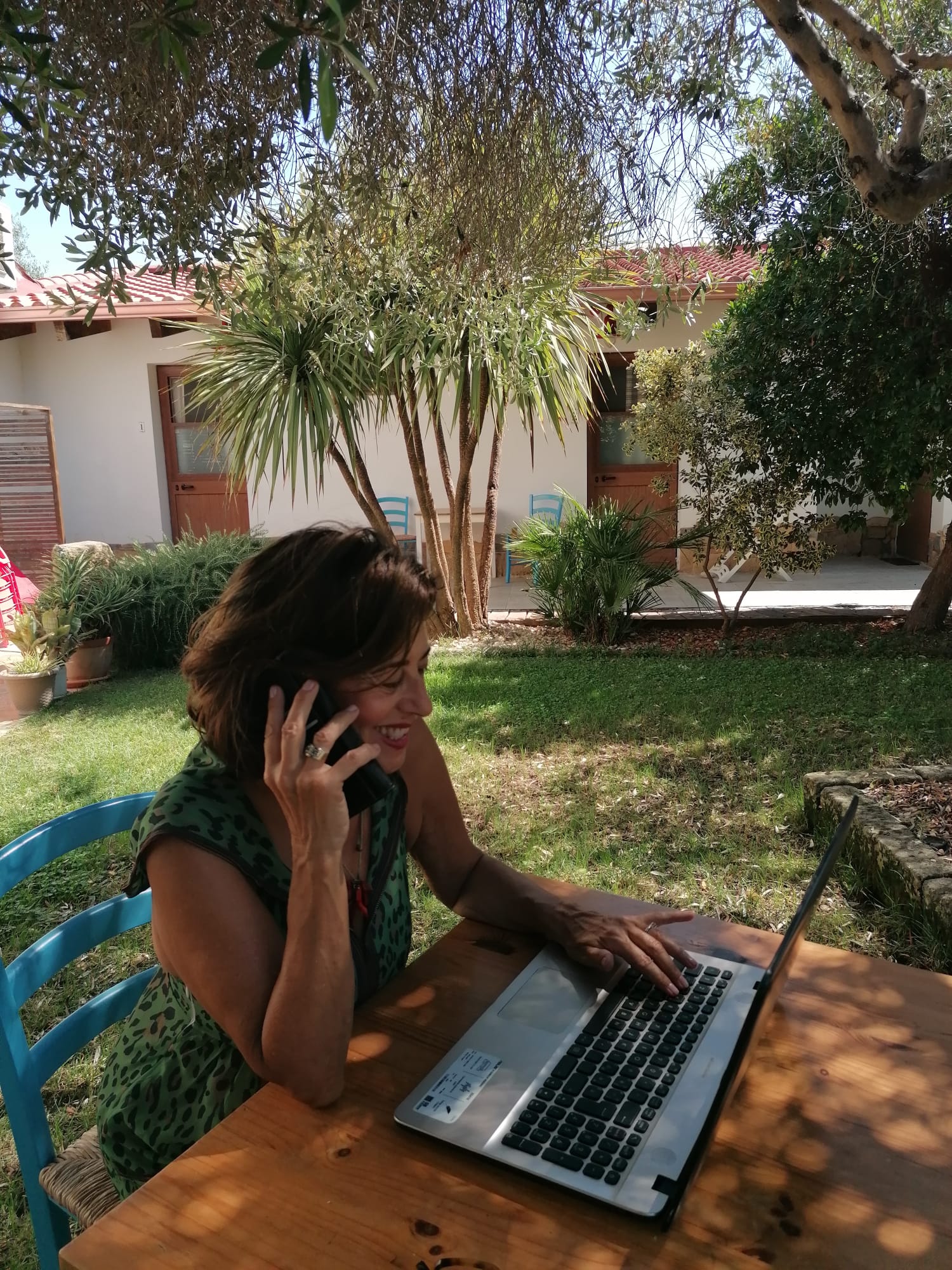 Maria Elena Righetti al telefono, sorridente, davanti al computer in giardino