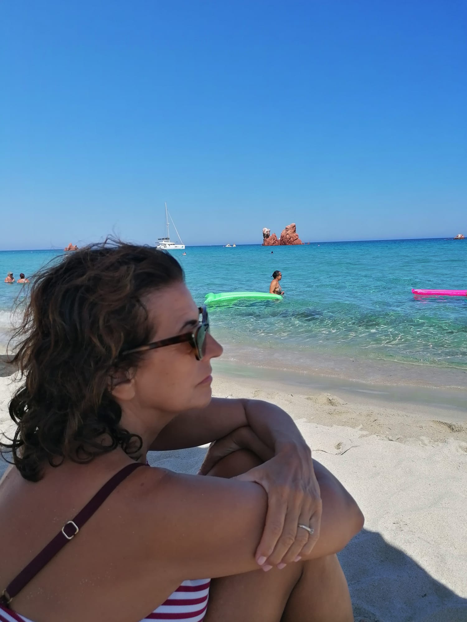 Maria Elena seduta sulla spiaggia guarda il mare turchese in Sardegna